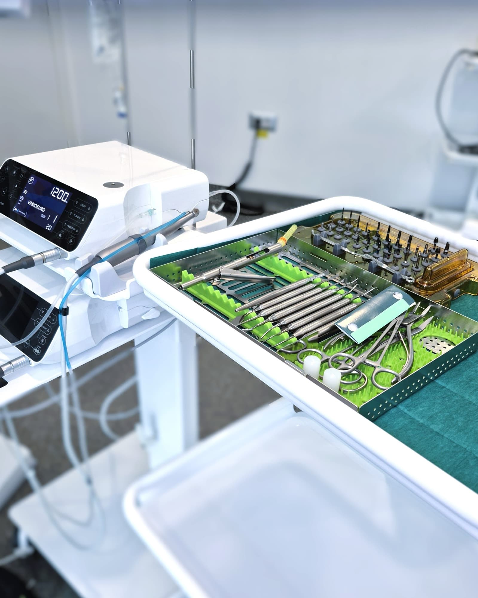 The implant surgery motor with its handpiece connected, next to the surgical kit laid out on a trolley, in the treatment room